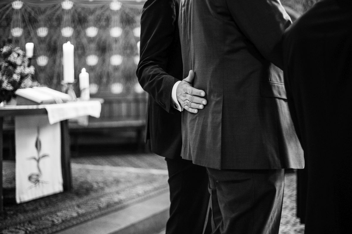 Ein Bräutigam hält seinen Mann mit der Hand am Rücken.